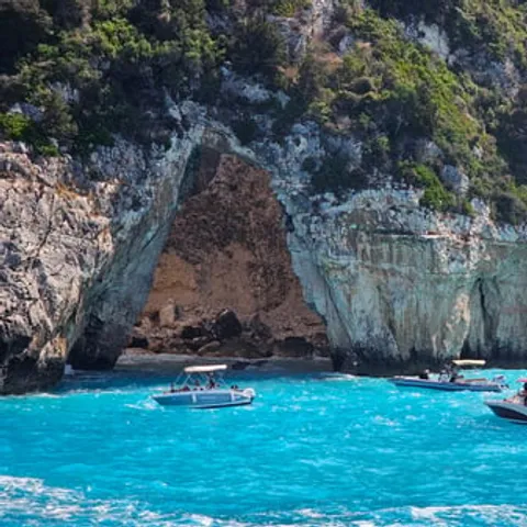 A boat below the arched sea cave on Paxos