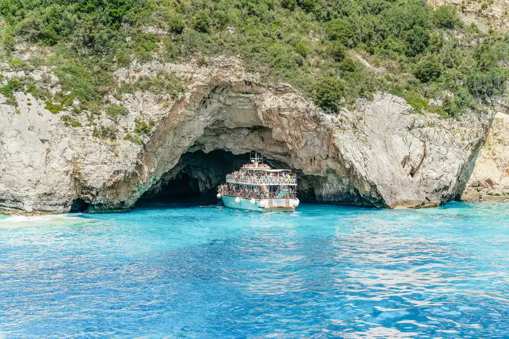 the boat dwarfed by the white cliffs at the mouth of a sea cave