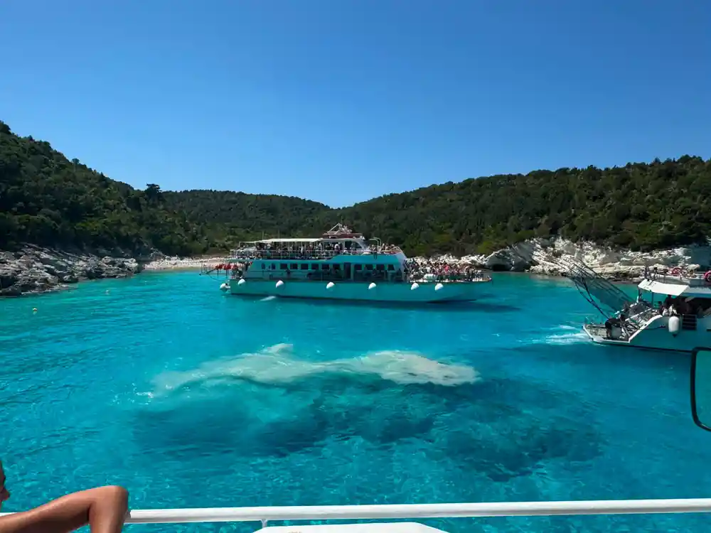 the cruise boat anchored in a turquoise bay with a sandbar showing
