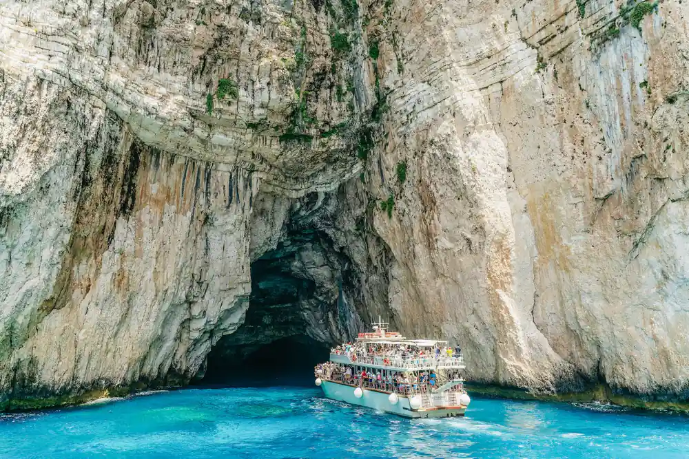 the cruise boat entering a high cave mouth in the white cliff face