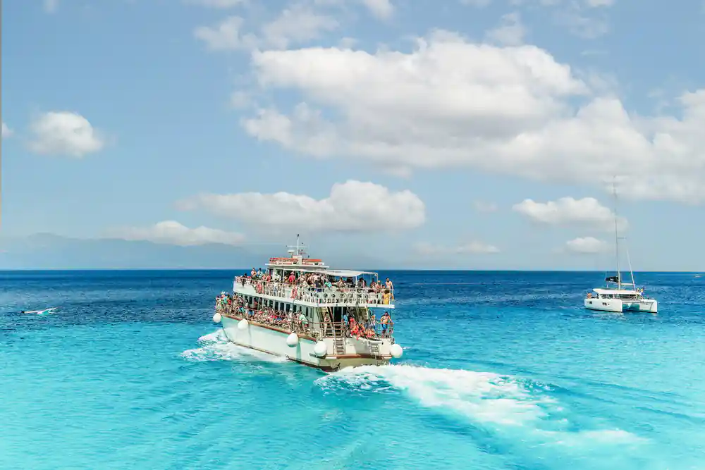 the cruise boat under way with its decks full of passengers on open blue water