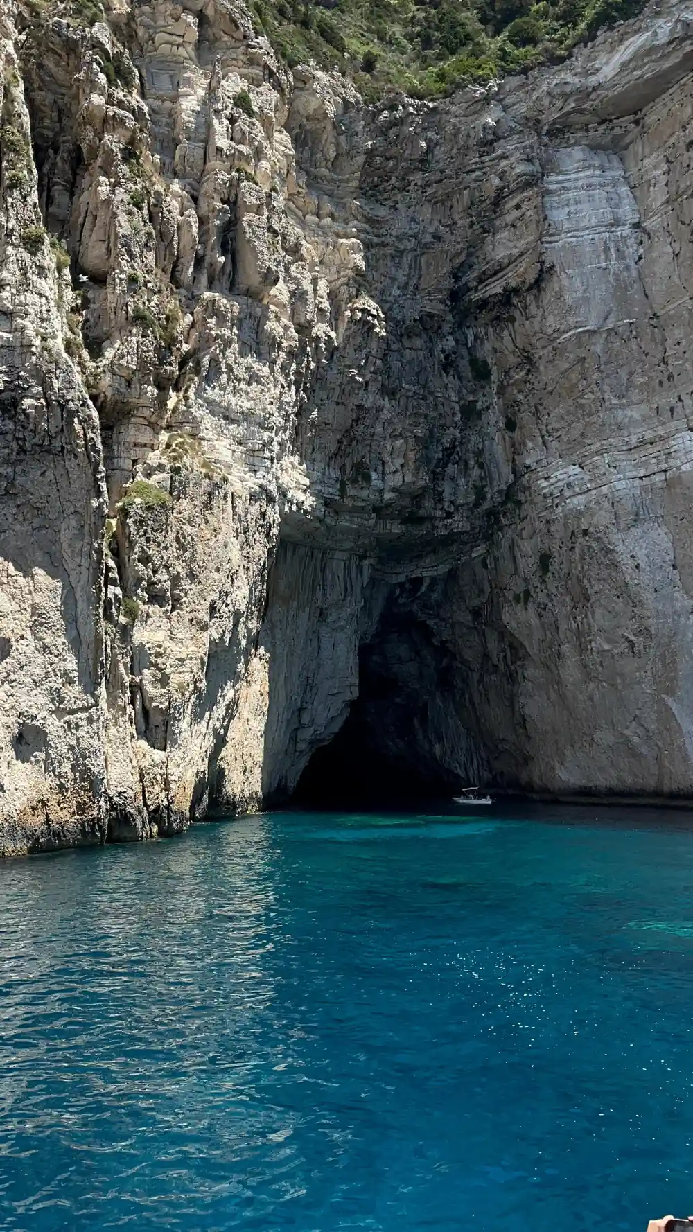 the dark mouth of a sea cave cut into layered white rock
