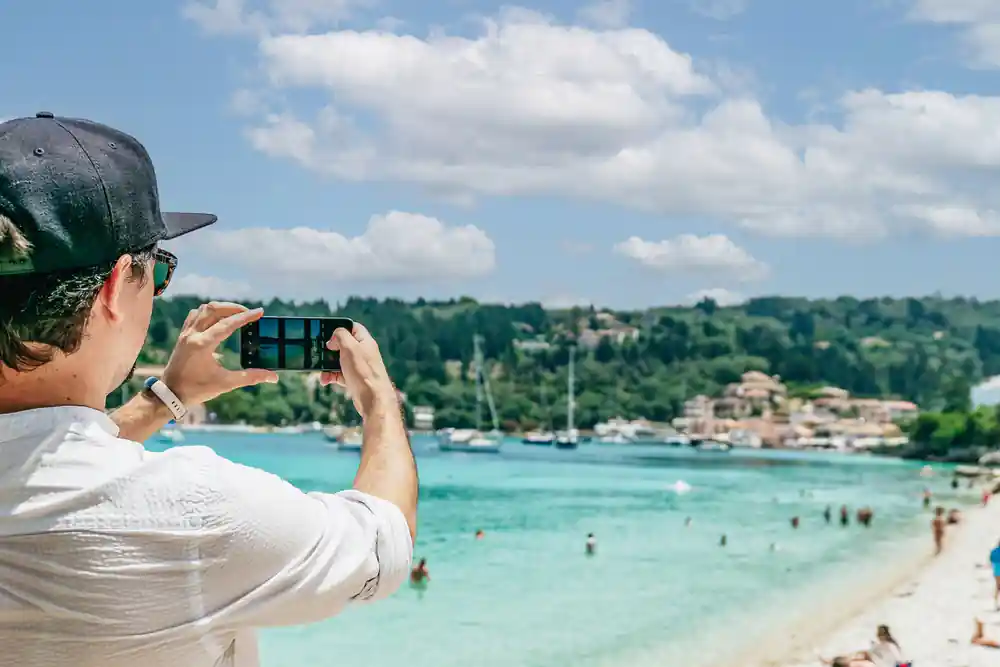 a guest photographing the bay from the deck with yachts and beach beyond