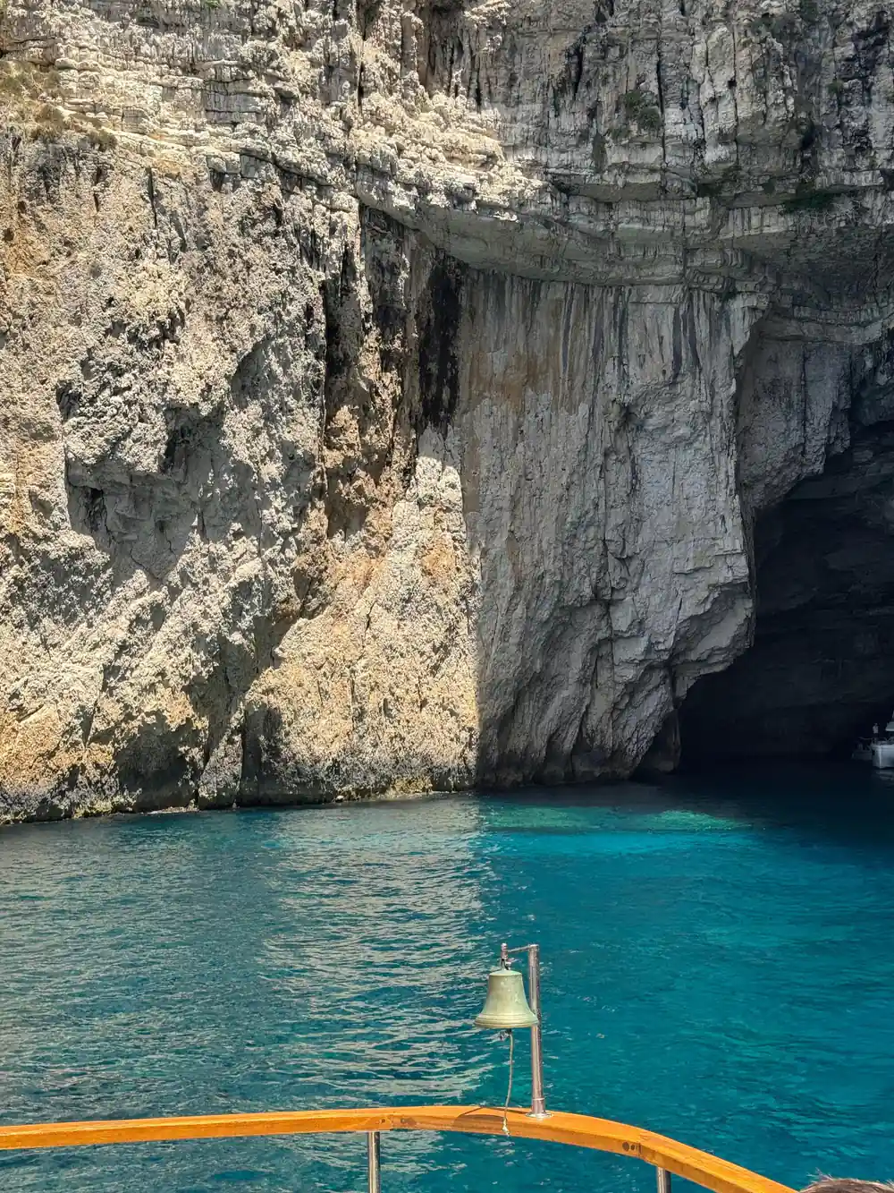 a huge cave mouth in tawny rock with the ship bell in the foreground