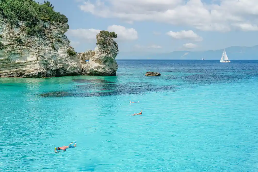 a limestone stack standing off a beach in clear turquoise water