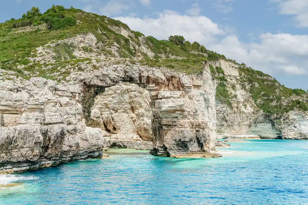 a natural rock arch in white limestone above clear water