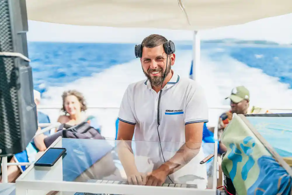 the onboard DJ at the decks with a guest beside him under the awning
