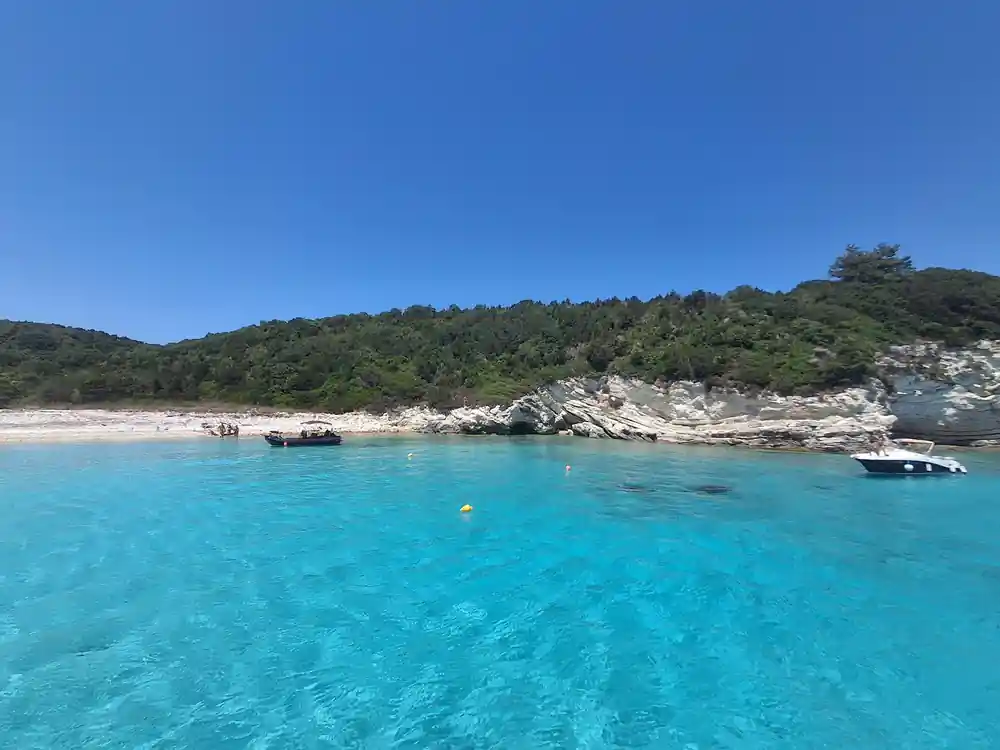 a pale beach and rocky point under a cloudless sky
