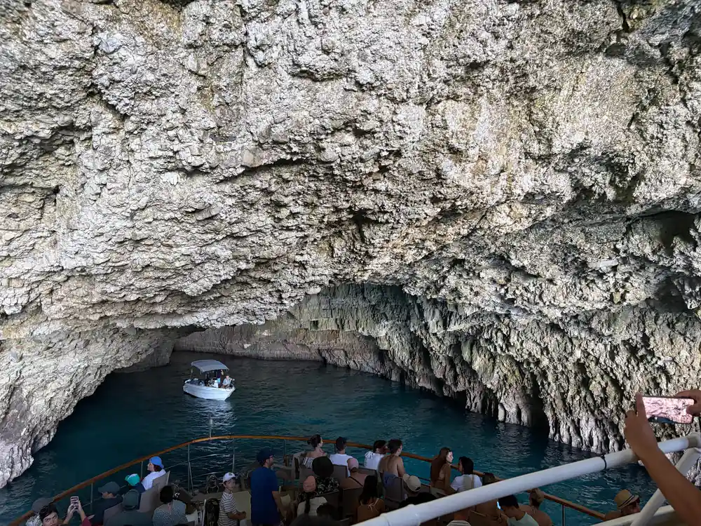 passengers on deck as the boat sits in the mouth of a cave