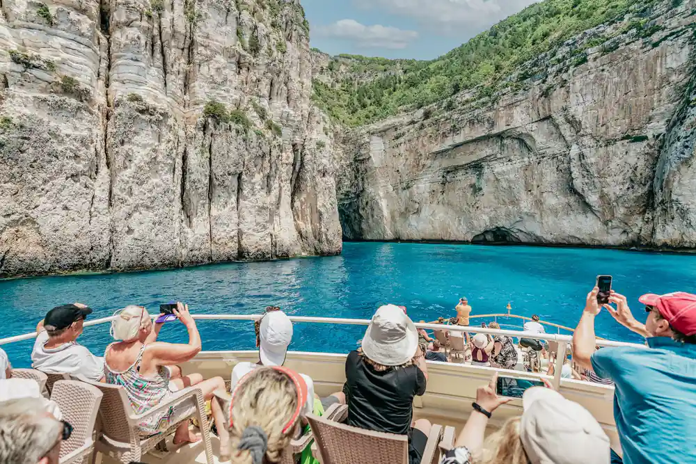 passengers in sun hats watching the cliffs pass from the shaded deck