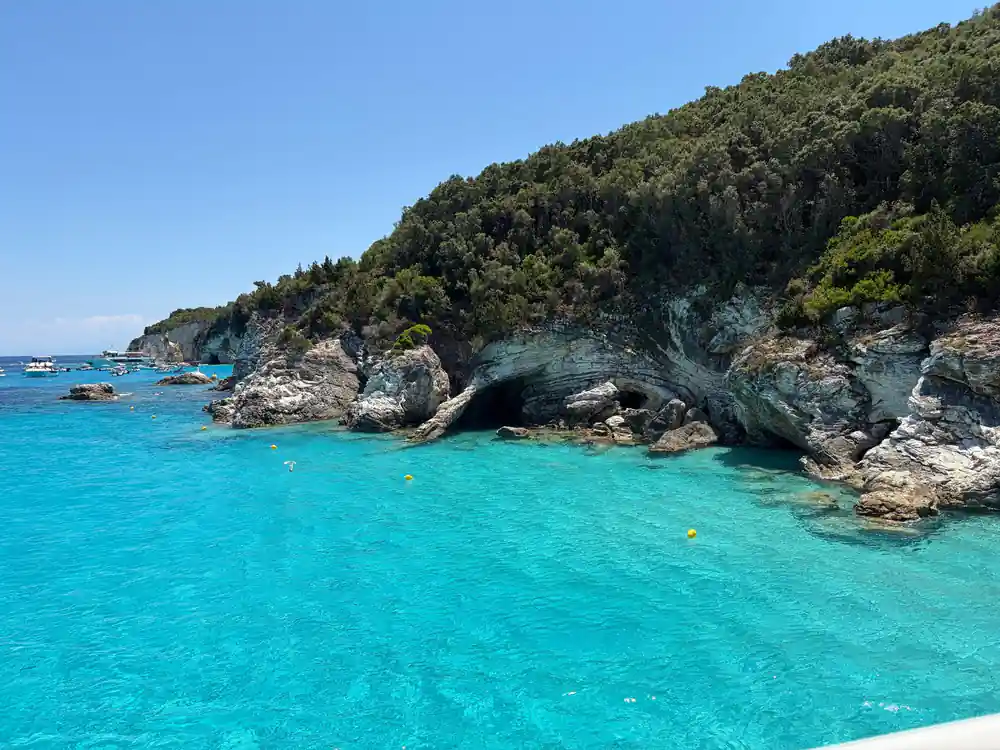 a rocky green promontory dropping into pale turquoise water