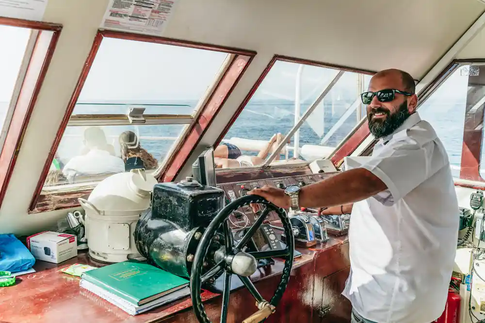 the skipper at the wooden wheel in the wheelhouse