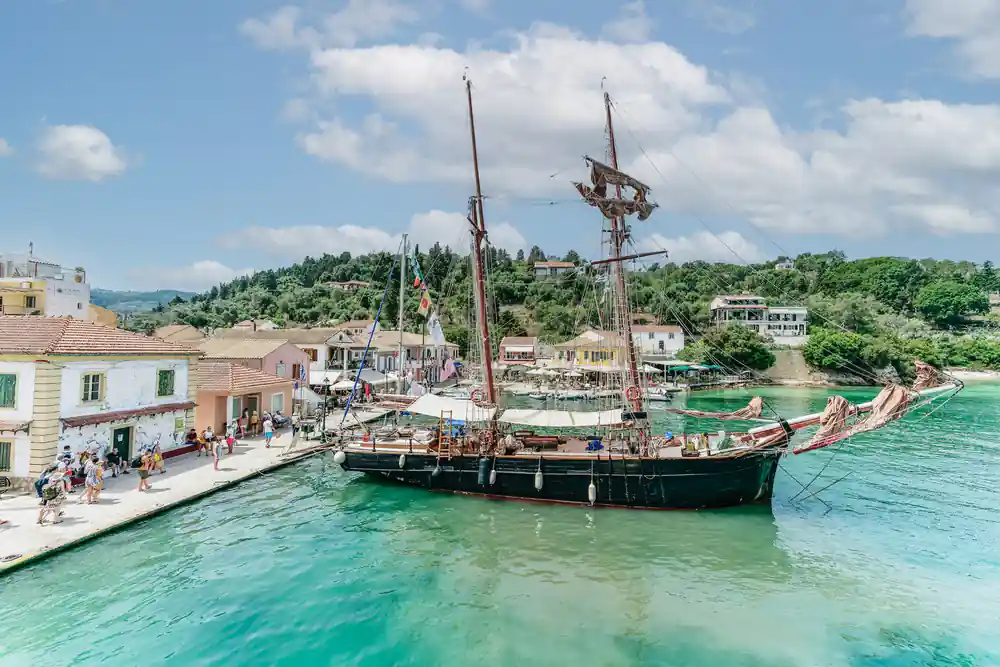 a tall-masted wooden vessel moored along the village waterfront