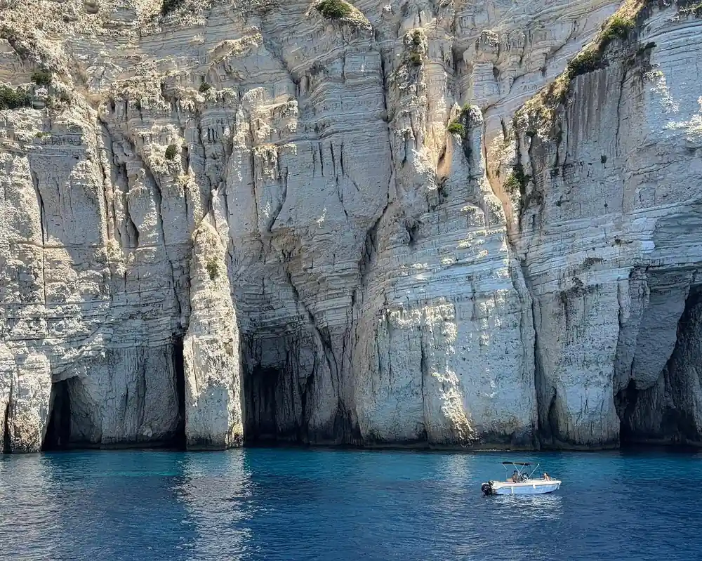 towering fluted white cliffs with small boats beneath for scale